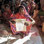 Frauen kämpfen für ihre Landrechte sitzen am Boden mit eine Dokument in den Händen